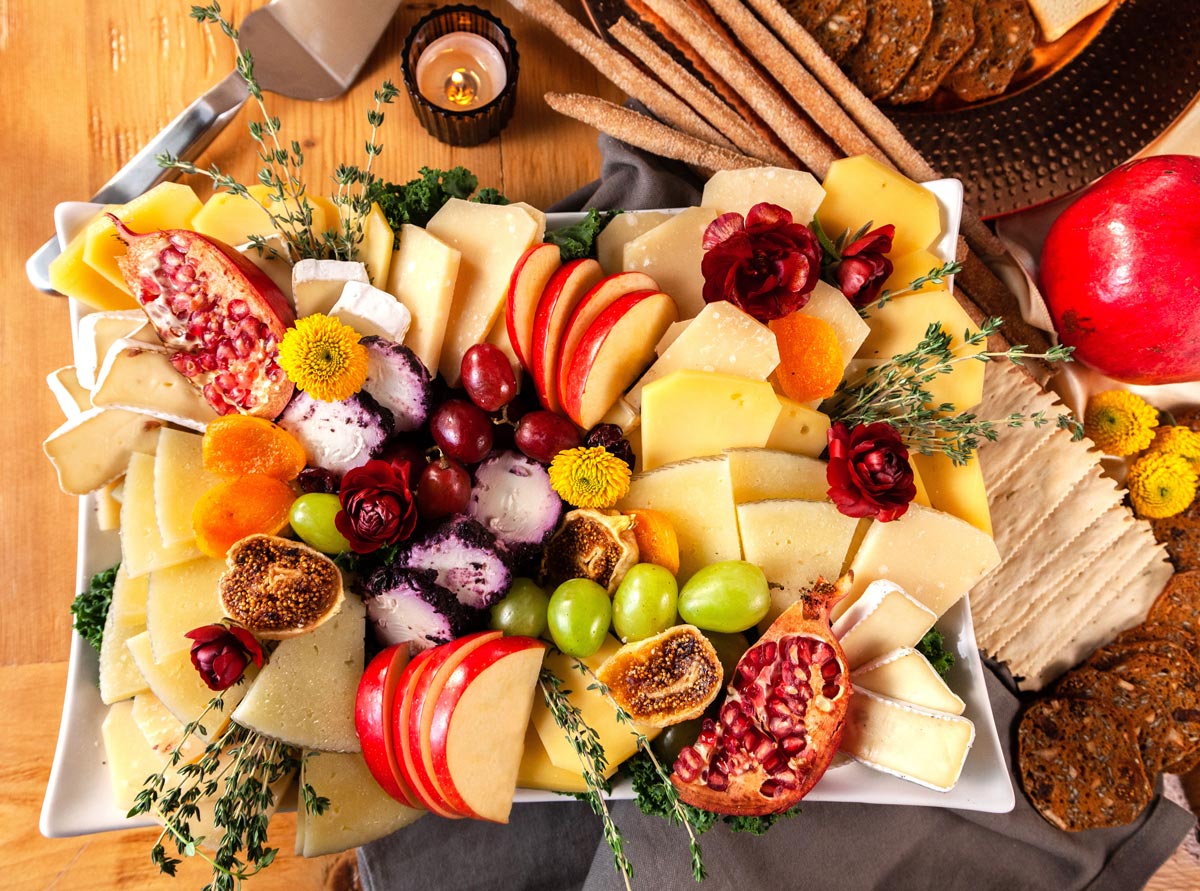 Photo of a cheese platter with assorted fruits and flowers
